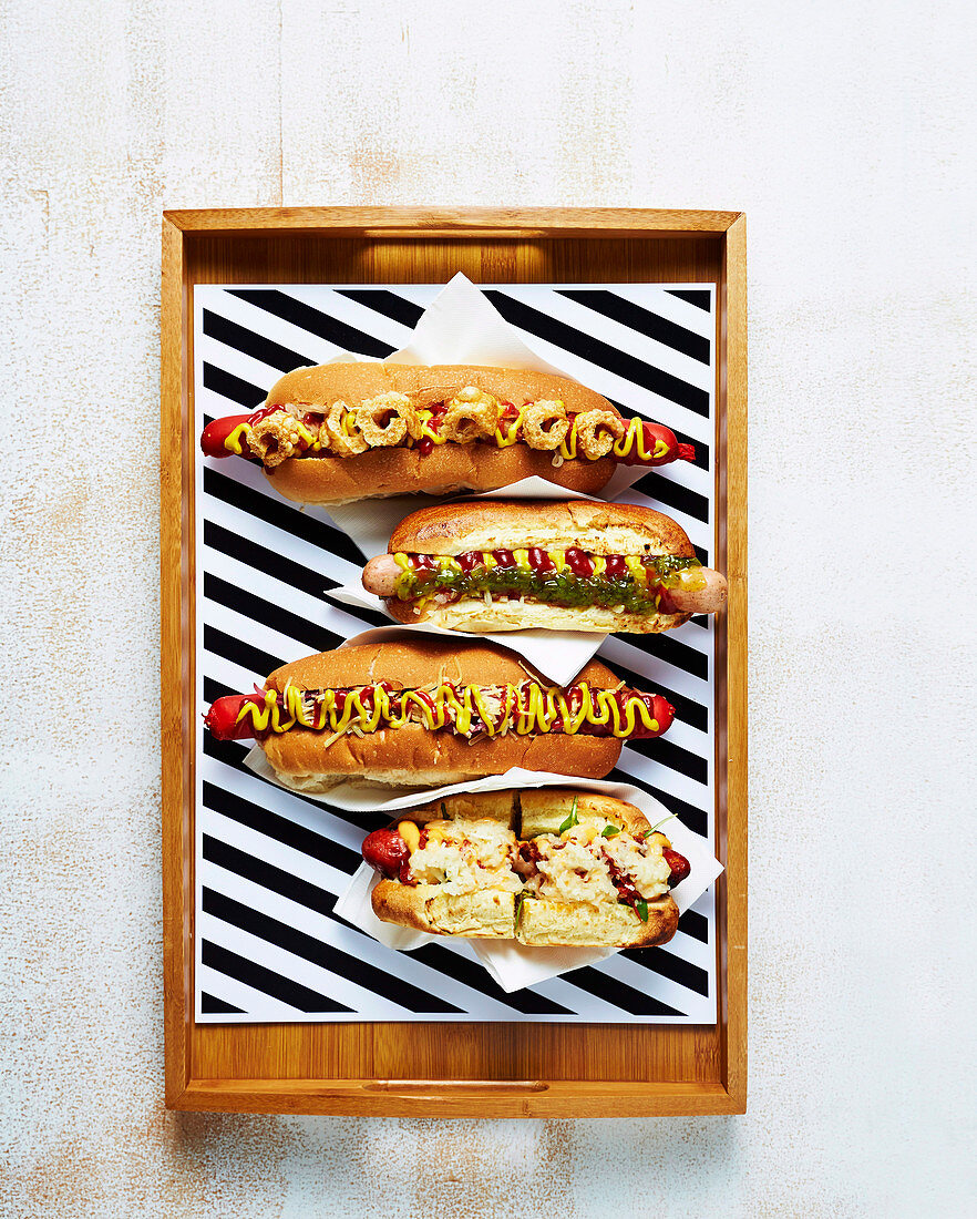 Vier verschiedene Hot Dogs auf Holztablett (Aufsicht)