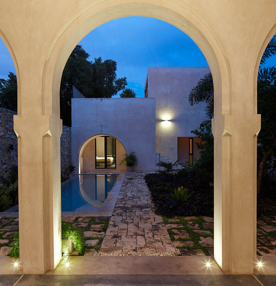 Abendlicher Blick durch einen Bogen auf den Innenhof mit Pool