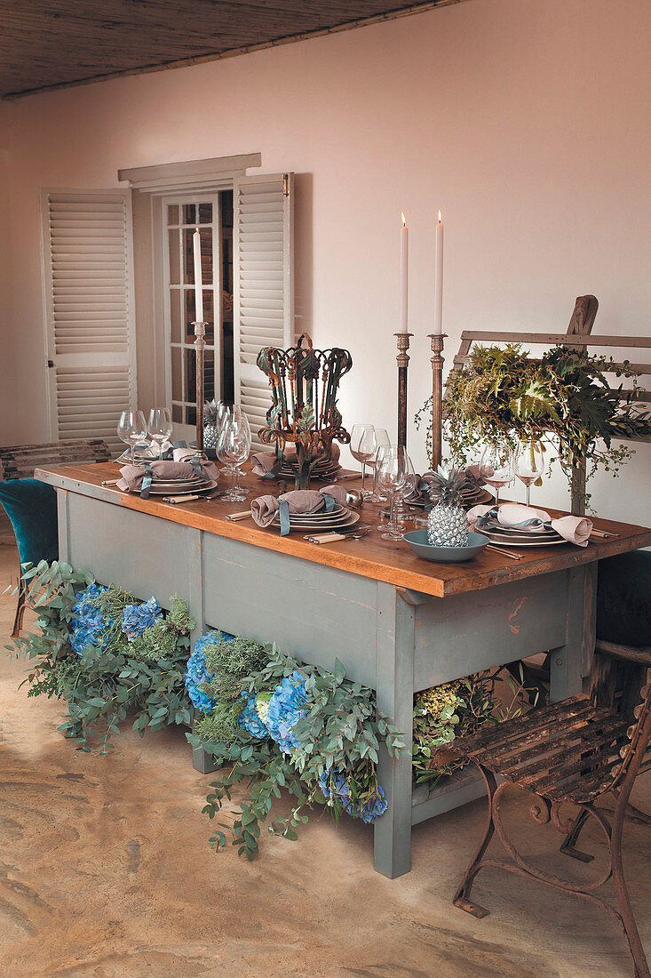 Table festively set with swathes of flowers and vintage accessories