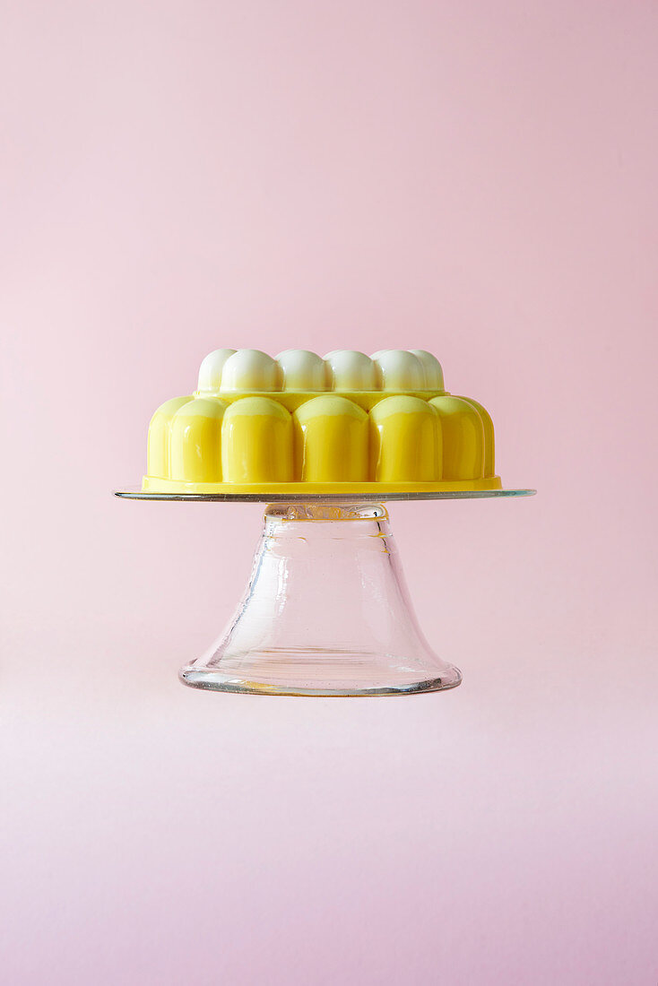 Zitronen-Baiser-Gelee auf Glasständer vor rosa Hintergrund