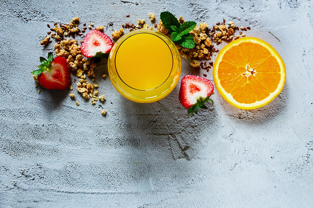 Frühstückszutaten: Orangensaft, Granola und Früchte (Aufsicht)