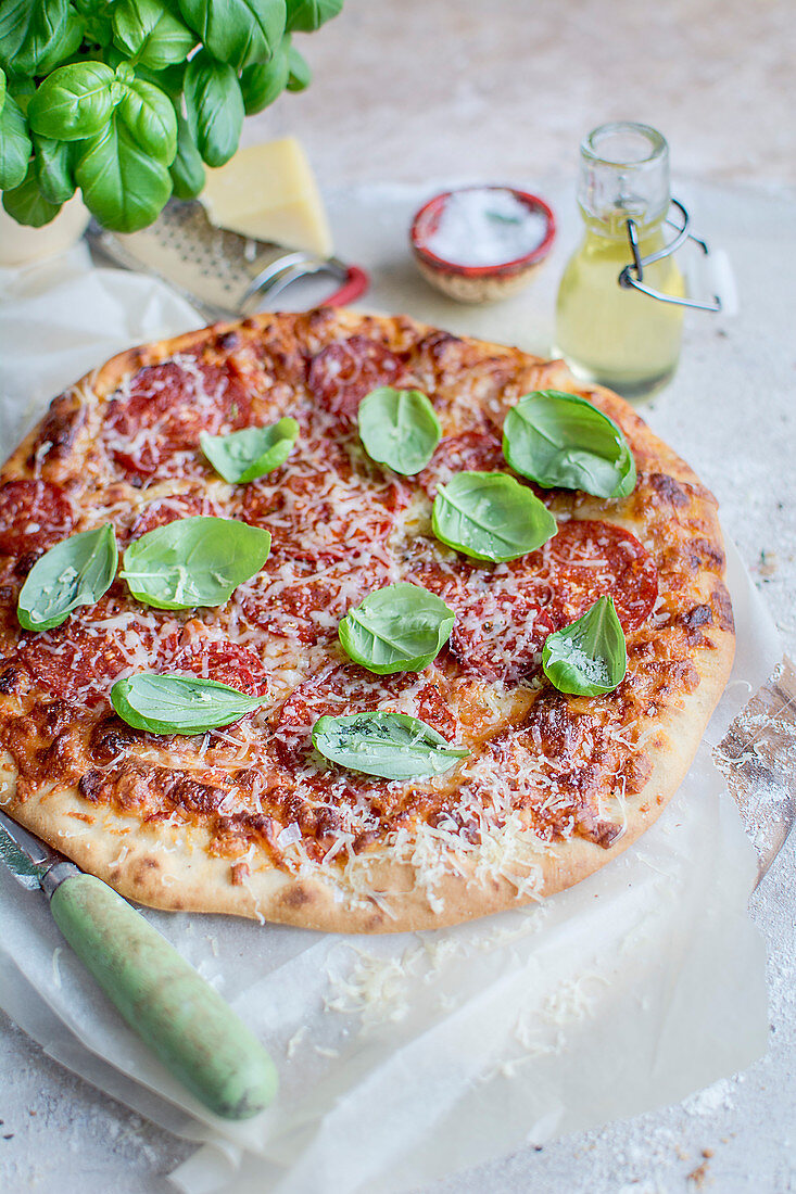 Pizza mit Peperoniwurst, Käse und Basilikum