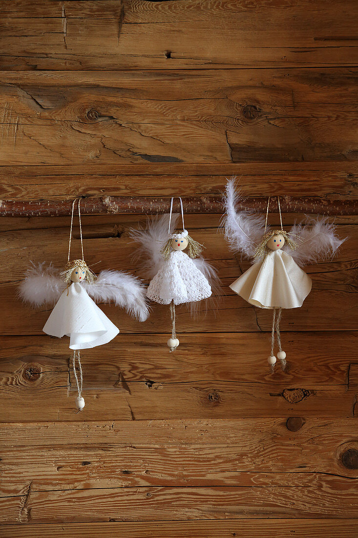 Handmade angels in white dresses on wooden wall