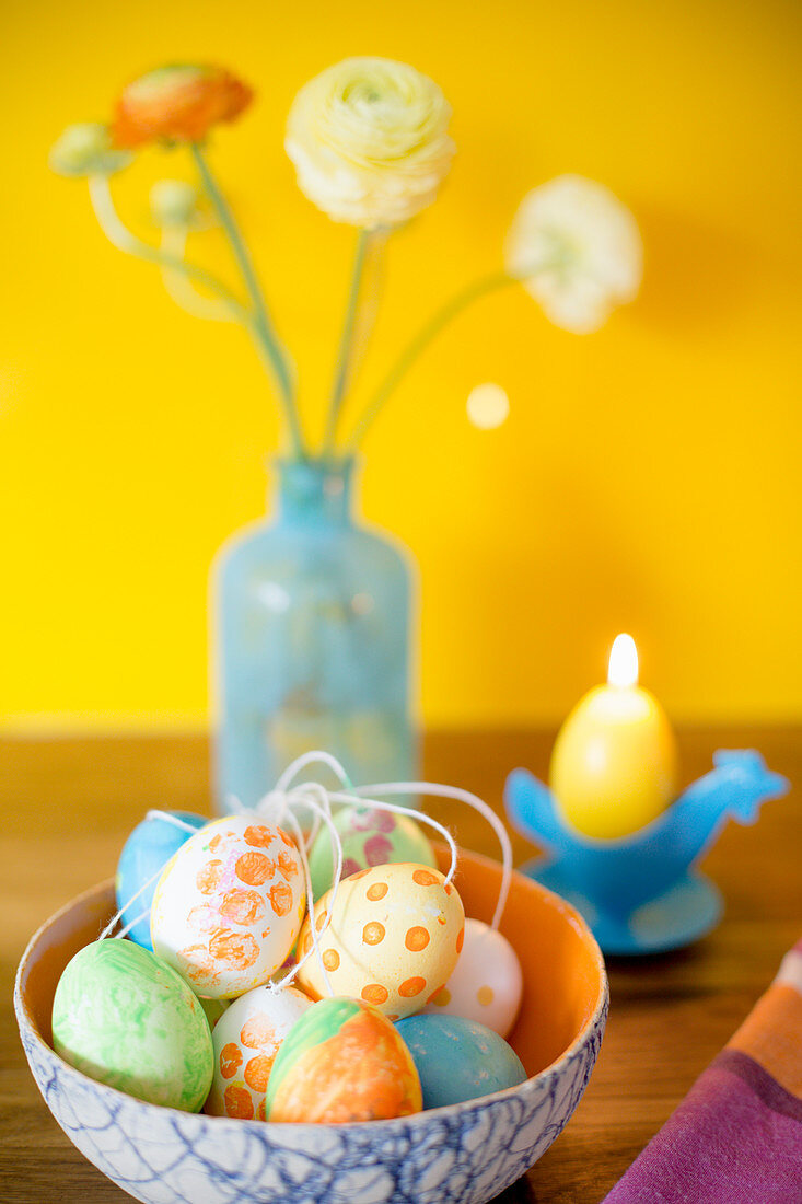 Easter eggs painted with gouache in front of candle and flowers