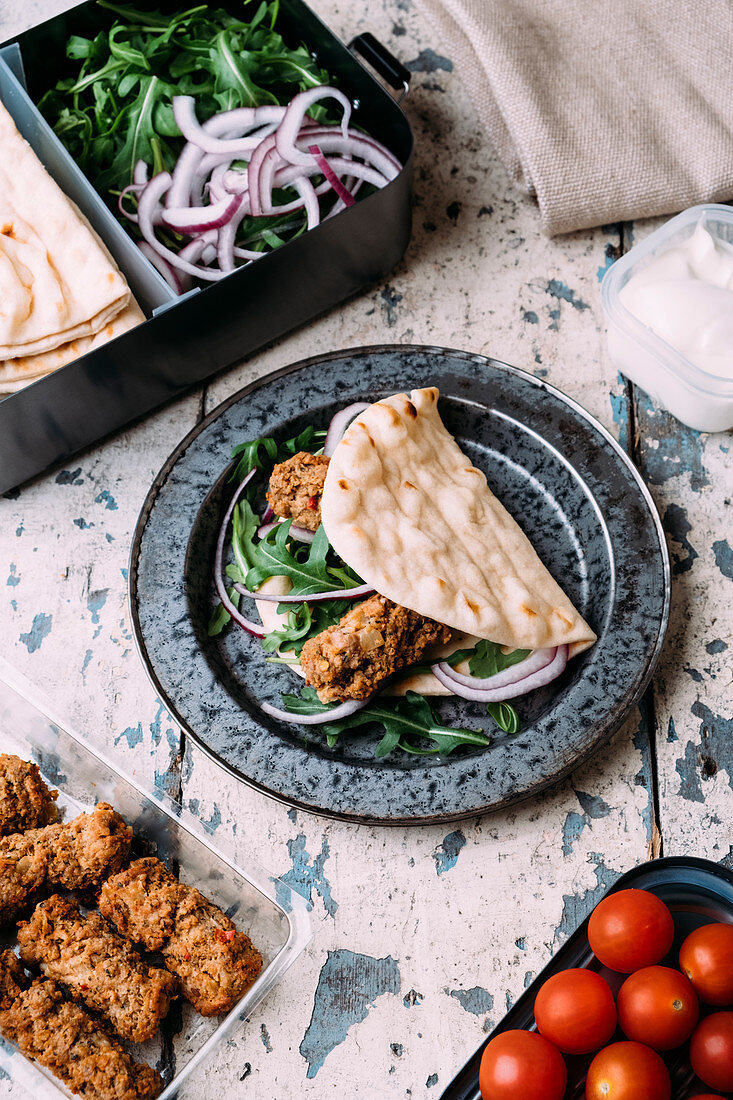 Lammköfte serviert mit Fladenbrot, Rucola, Zwiebeln, Tomaten und Joghurt