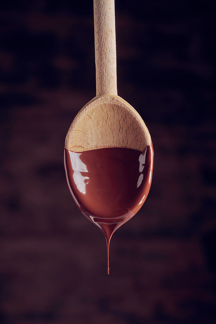 Liquid chocolate dripping from a wooden spoon