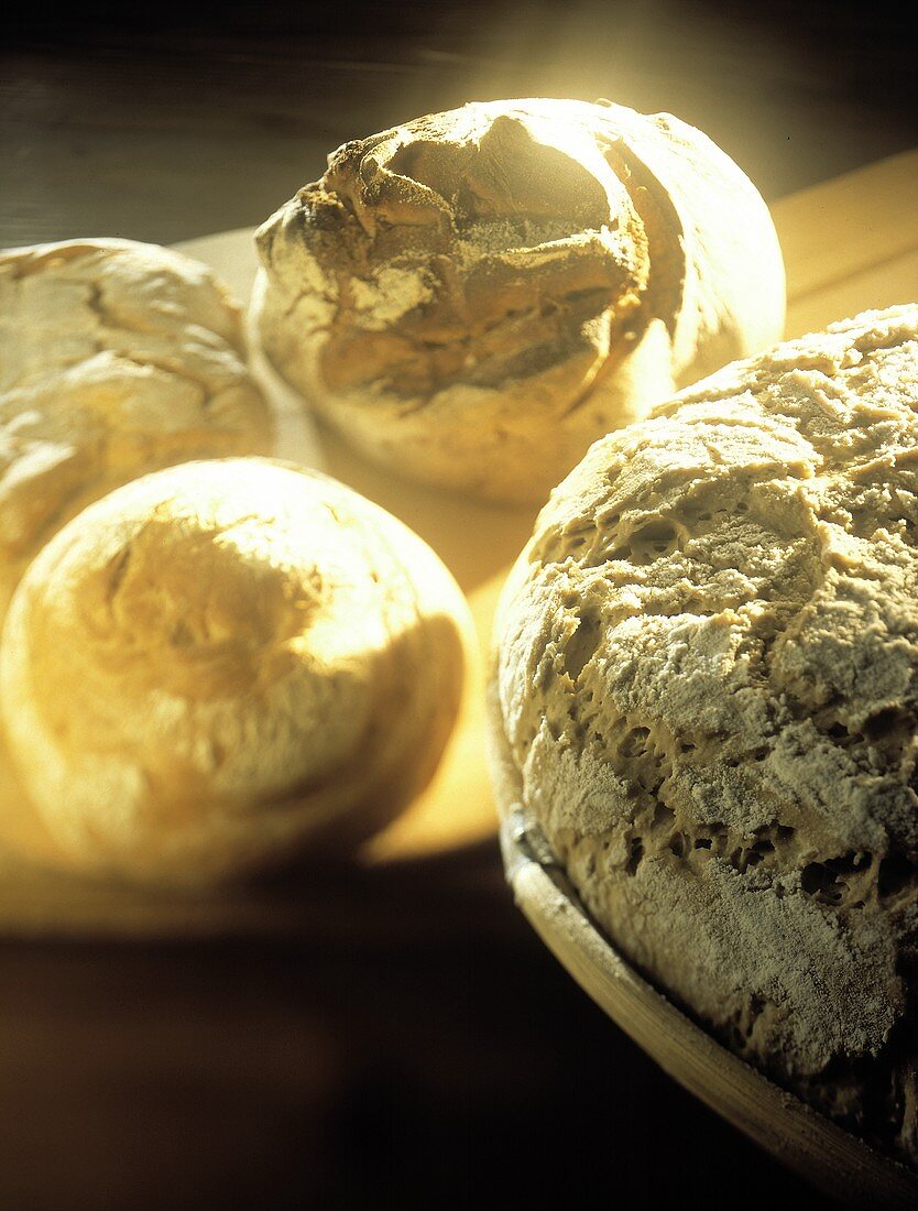 Drei Brote & etwas Brotteig auf Holzbrett