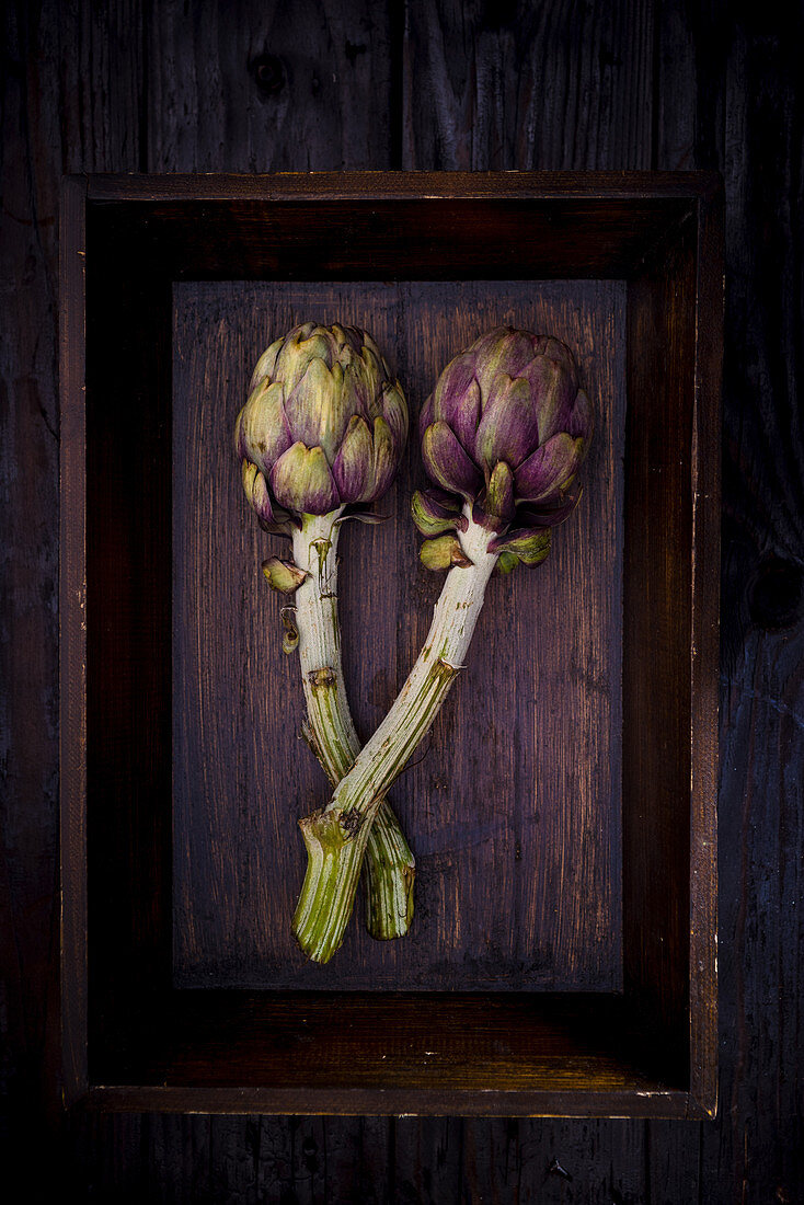 Two Artichokes on a wooden tray