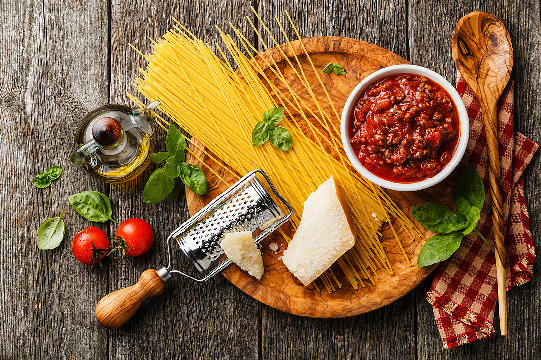 Zutaten für Spaghetti Bolognese auf Holzbrett und Holzuntergrund (Aufsicht)
