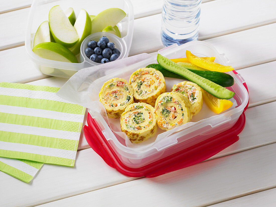 Omelette rolls with vegetable sticks, fruit and water for lunch