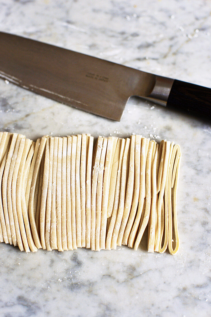 Oriental noodle dough being cut into strips