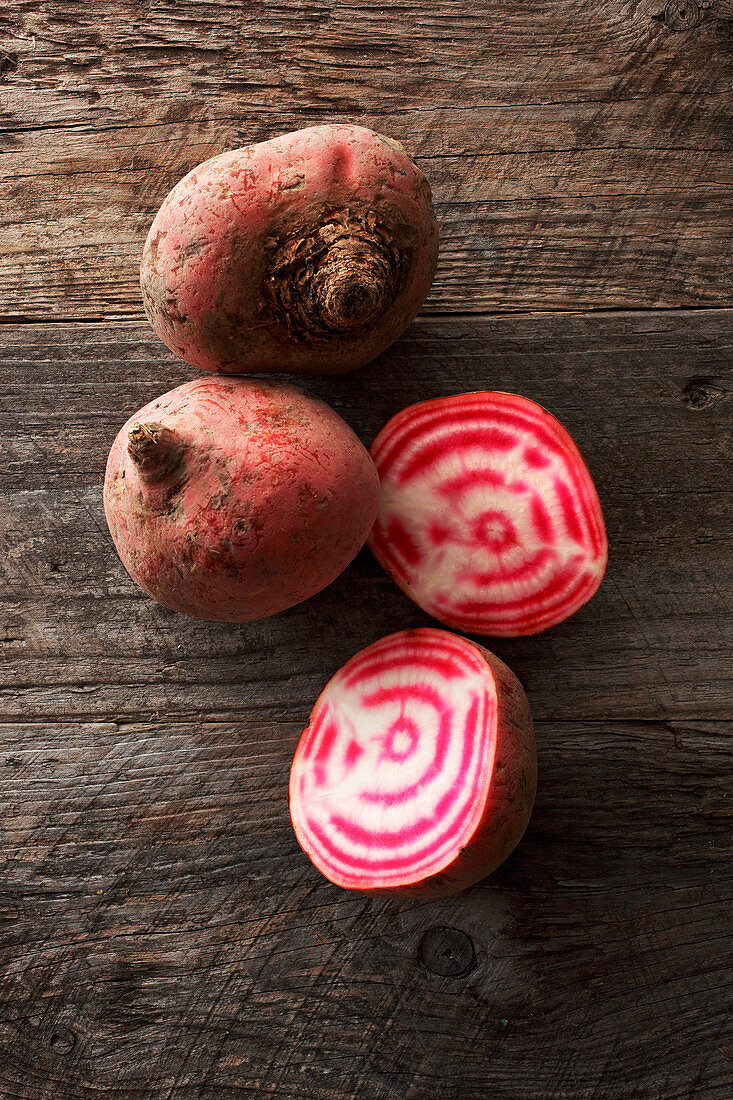 Chioggia beets, whole and halved on a wooden surface