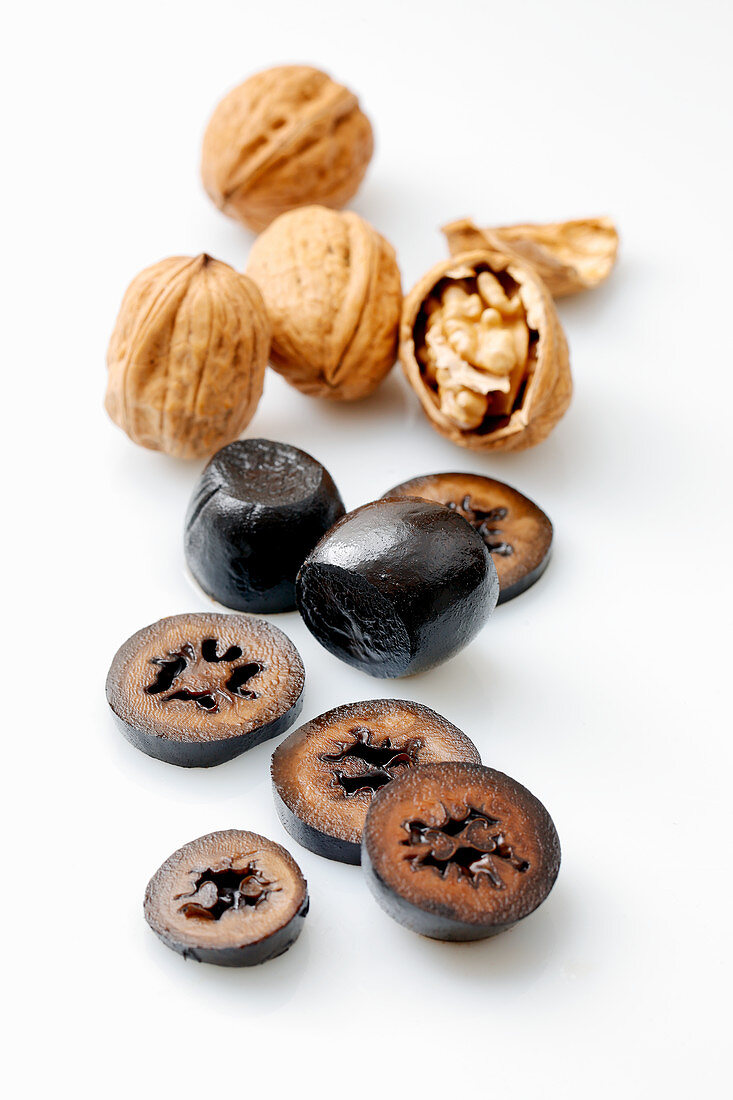 Walnuts, fresh and pickled, against a white surface