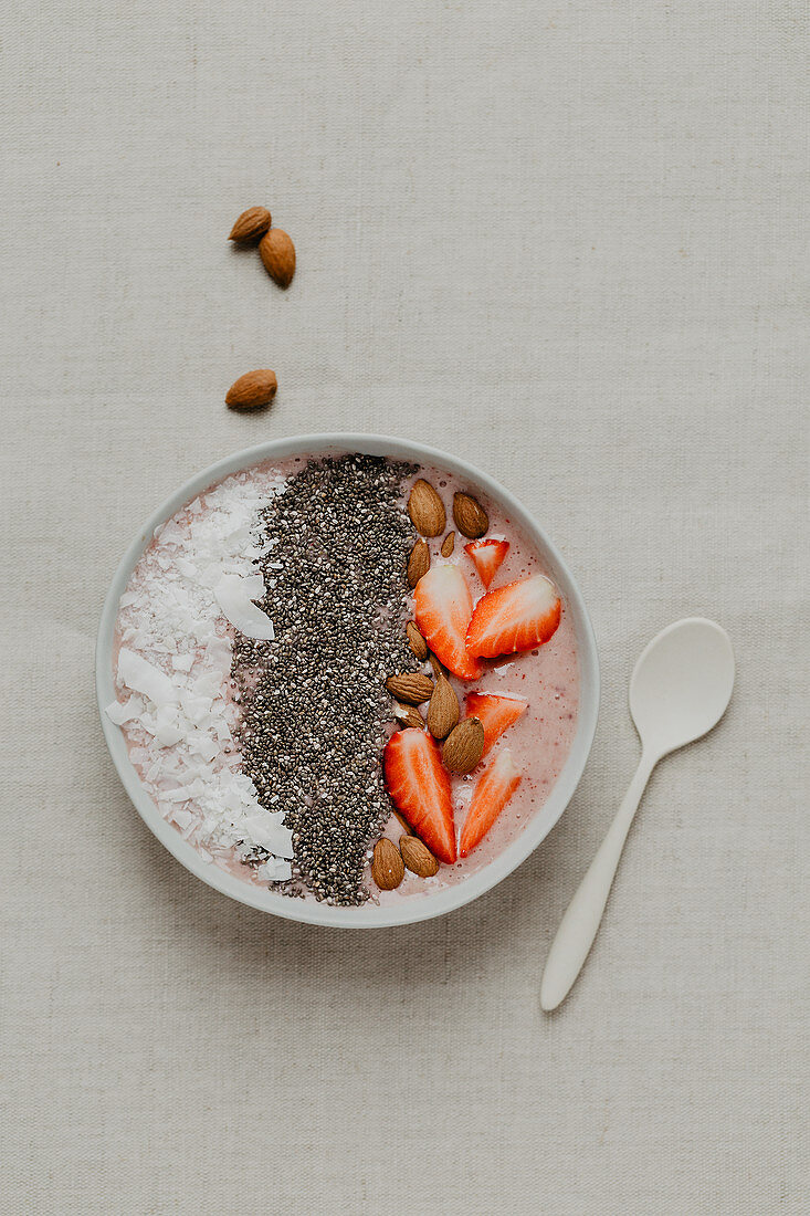 A smoothie bowl with strawberries, chia, almonds and coconut flakes