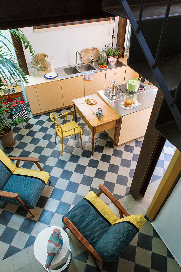 Blick auf offene Küche mit Sitzmöbeln auf Schachbrettmusterboden
