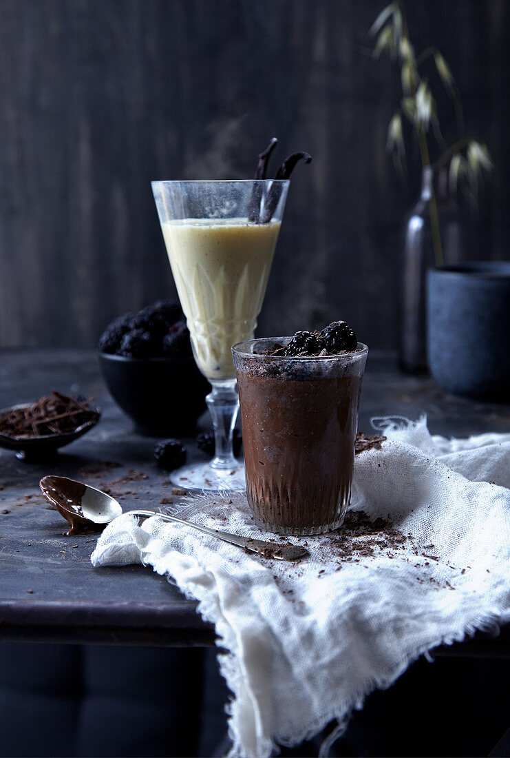 Dunkler Schokoladenpudding und heißer Vanilledrink in Gläsern
