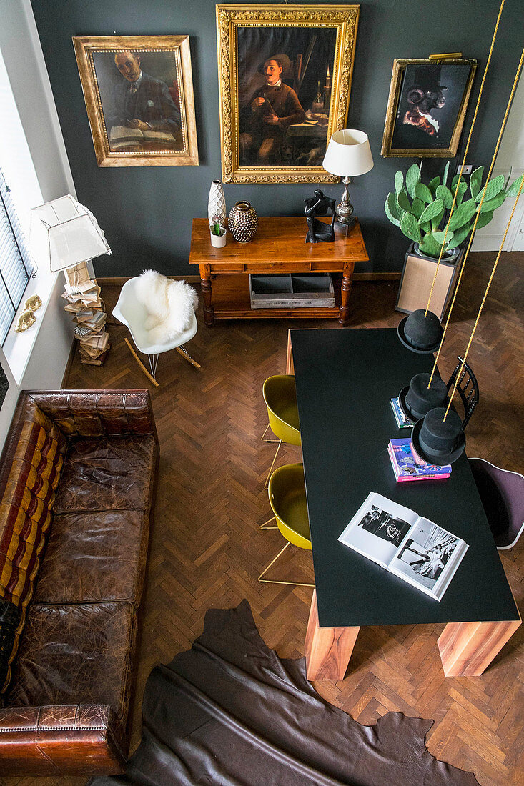 View down onto table, shell chairs, vintage leather couch and gilt-framed pictures