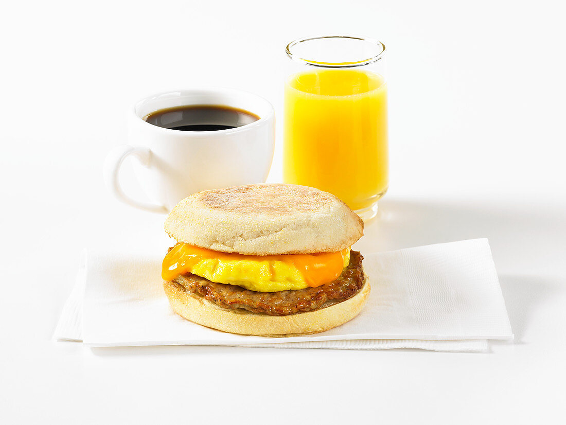 An English muffin with sausage, coffee and orange juice for breakfast