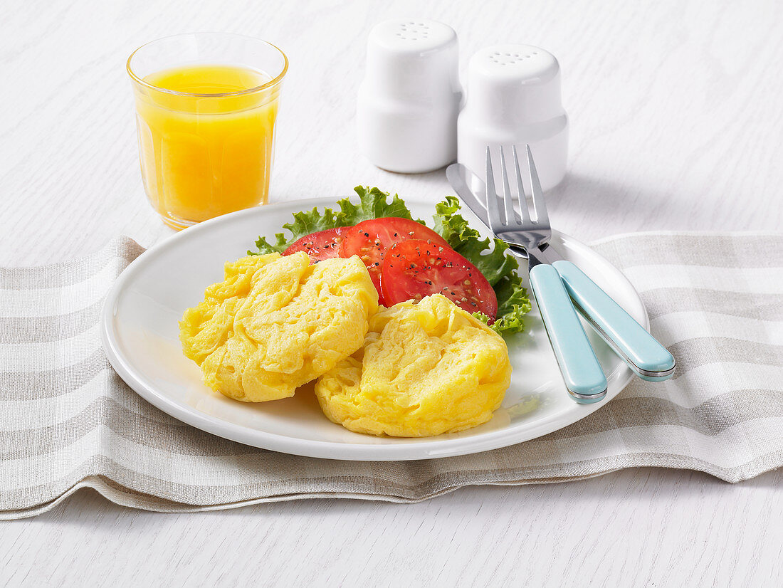 Egg patties with tomatoes and a glass of orange juice