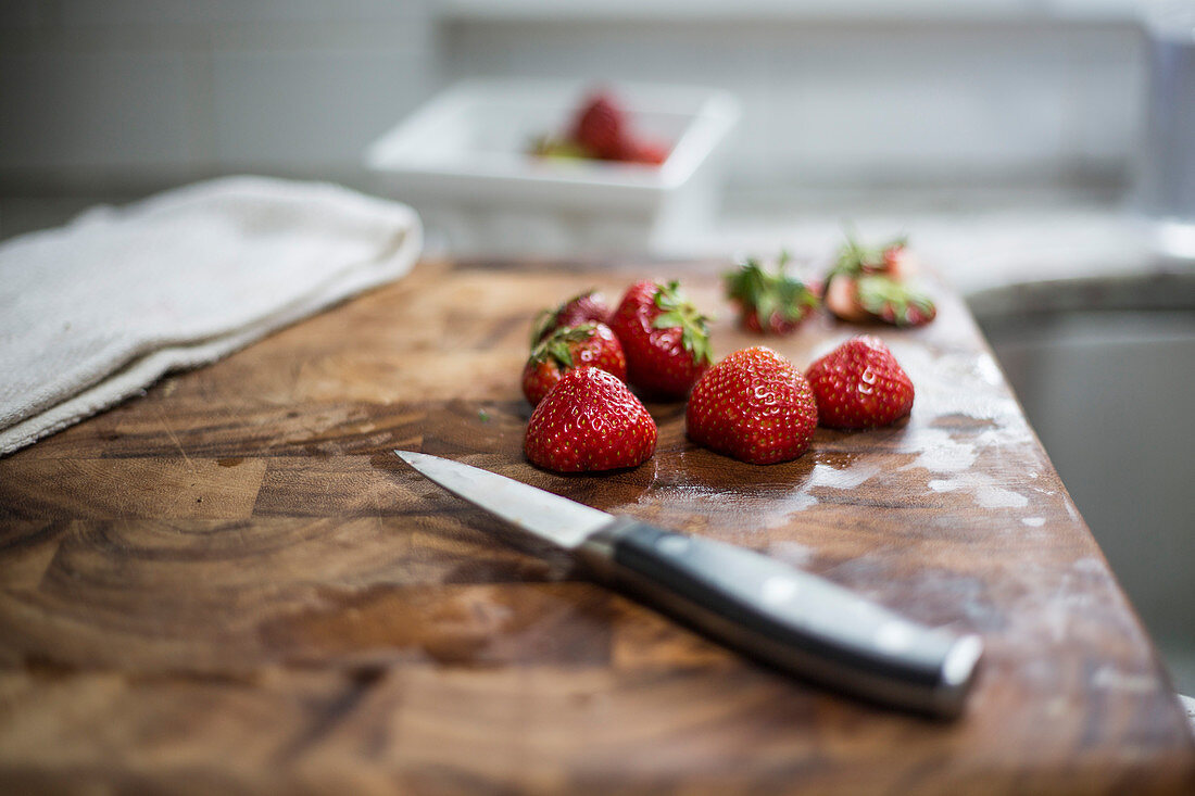 Erdbeeren auf Holzbrett mit Messer und Küchentuch