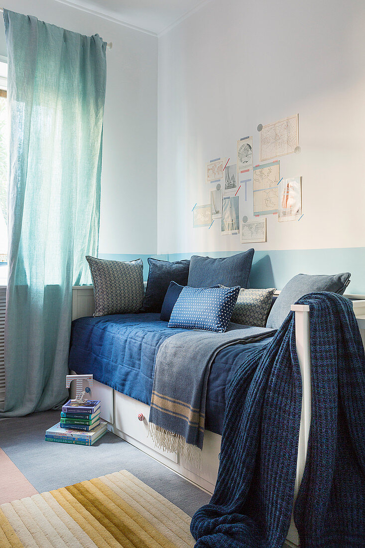 Bildercollage über dem Bett mit verschiedenen blauen Kissen