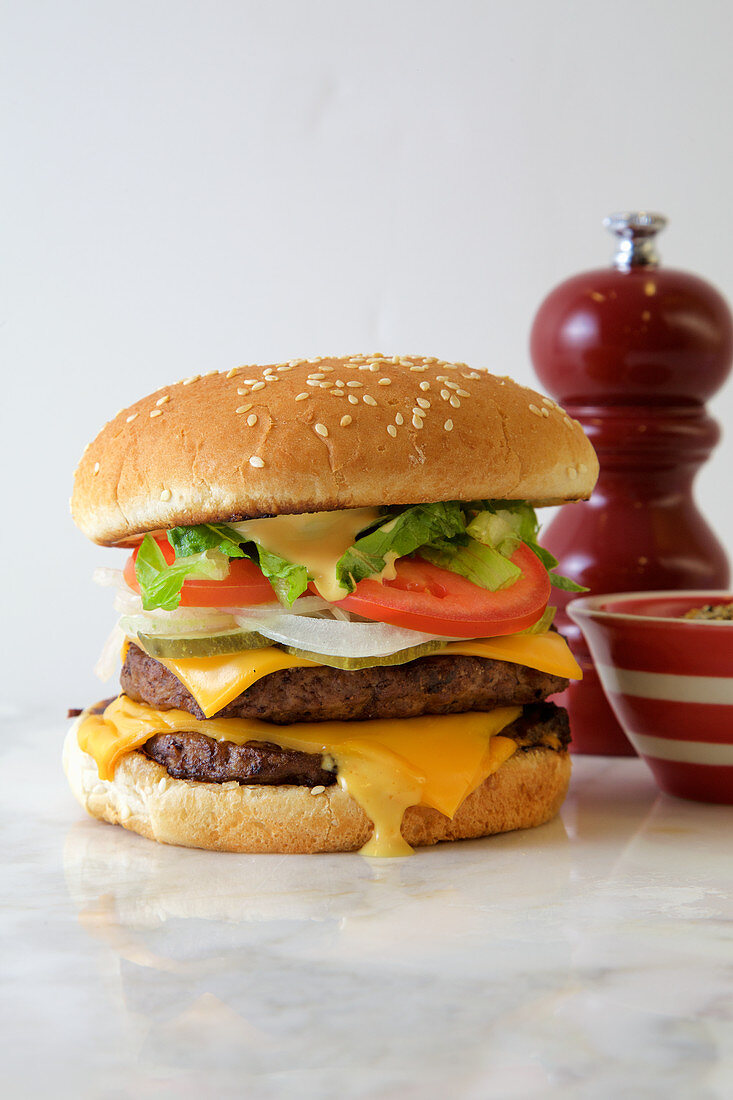 Double Burger with american cheese, lettuce and tomato on a white background, with extra spices