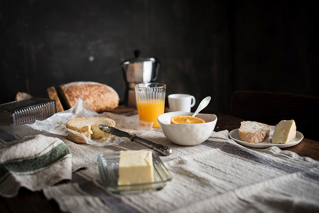 Frühstückstisch mit Kaffee, Orangensaft, Brot, Butter und Käse