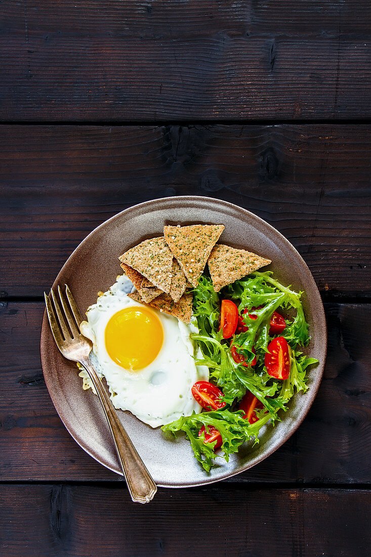 Vegetarian breakfast with a fried egg, salad and crackers (seen from above)