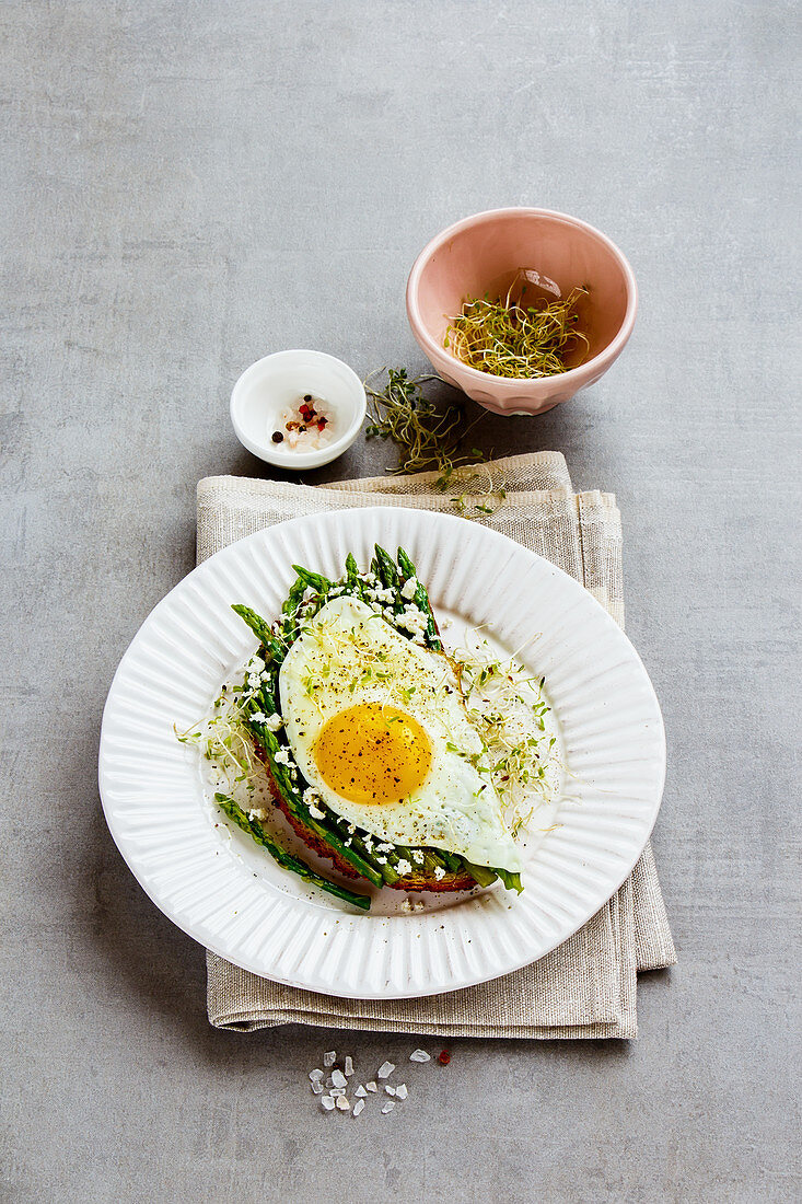 A spring sandwich with green asparagus, a fried egg, feta cheese and beansprouts