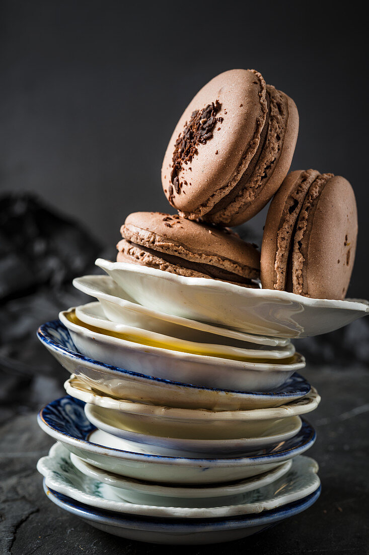 Three chocolate macaroons on a stack of plates
