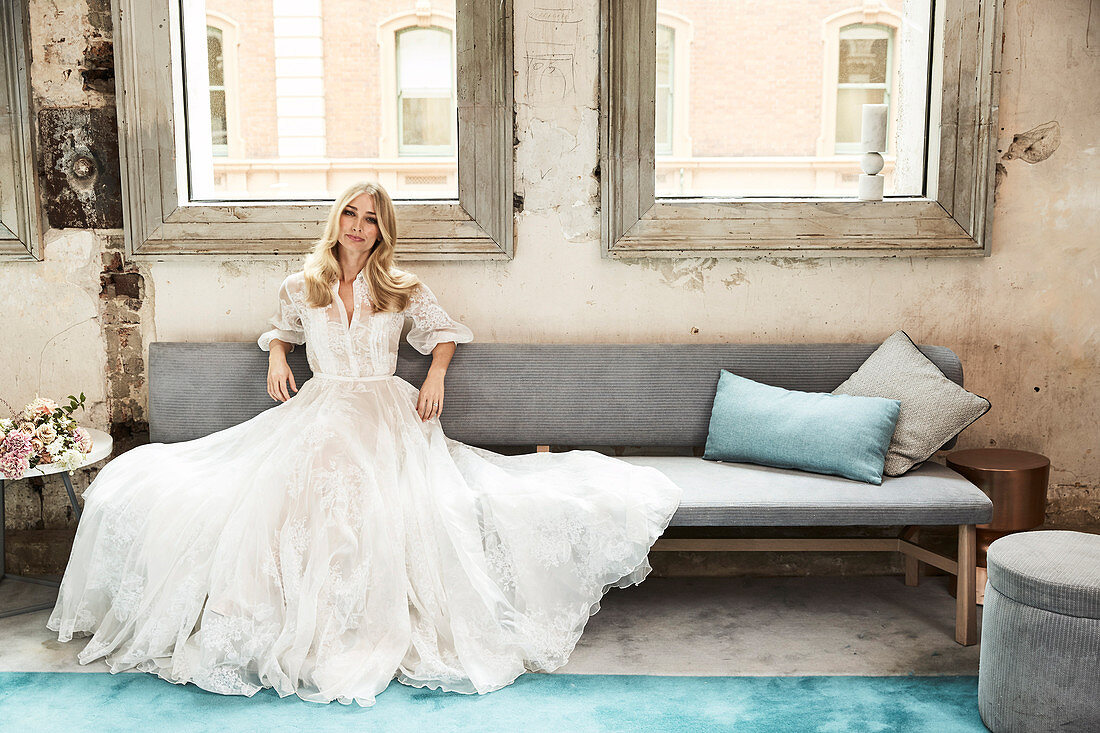 A blonde woman wearing a long wedding dress in a vintage room