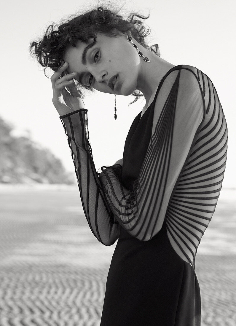 A dark-haired woman wearing a black, partially transparent dress (black-and-white shot)