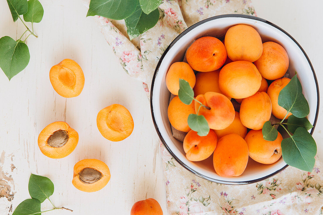 Apricots in a bowl and on a flowered cloth