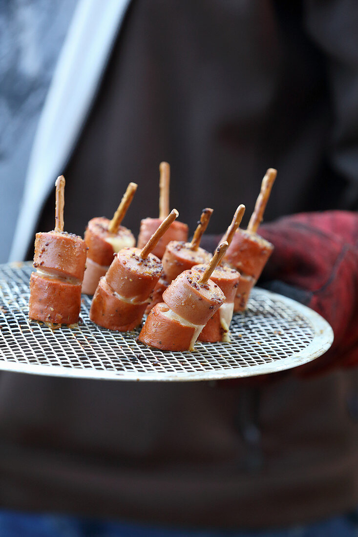 Grilled sausages with honey and mustard sauce on pretzel sticks