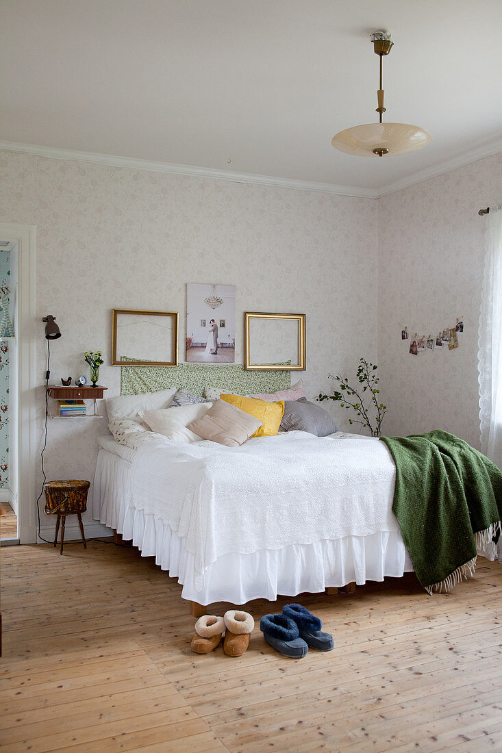 Bett mit Husse im nostalgischen Schlafzimmer mit Dielenboden