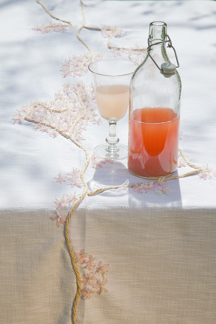 Soft drink in bottle on handmade tablecloth with cherry blossom pattern