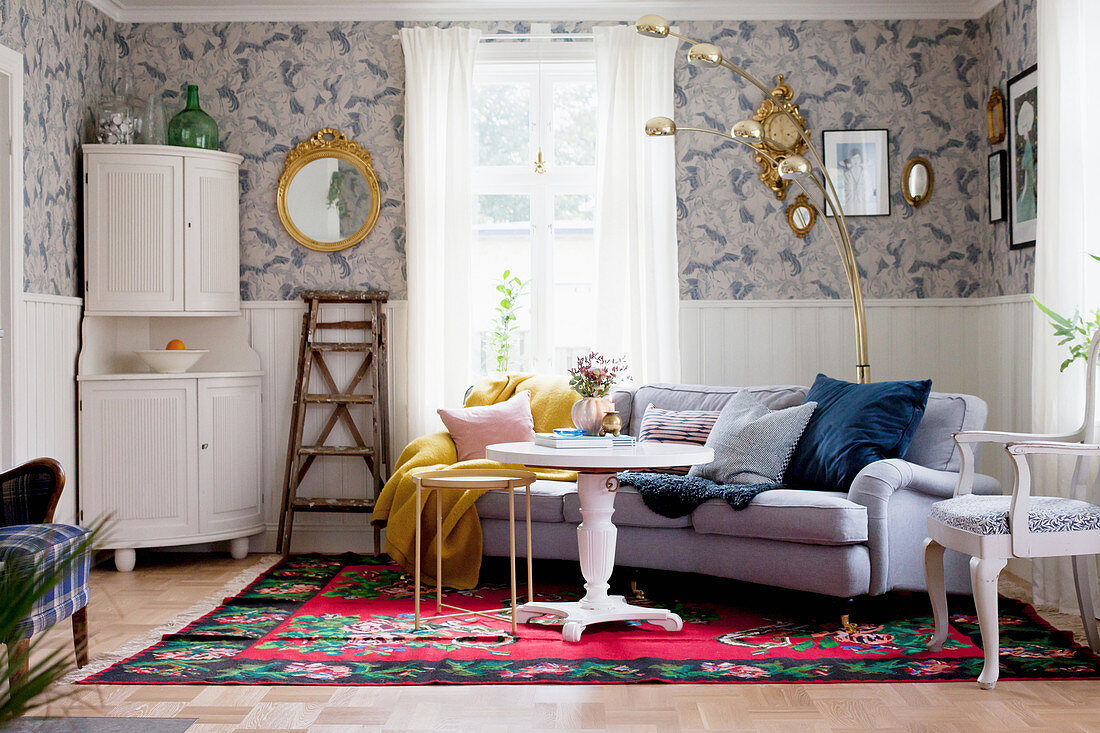 White corner cabinet, round white table and sofa on rug in living room