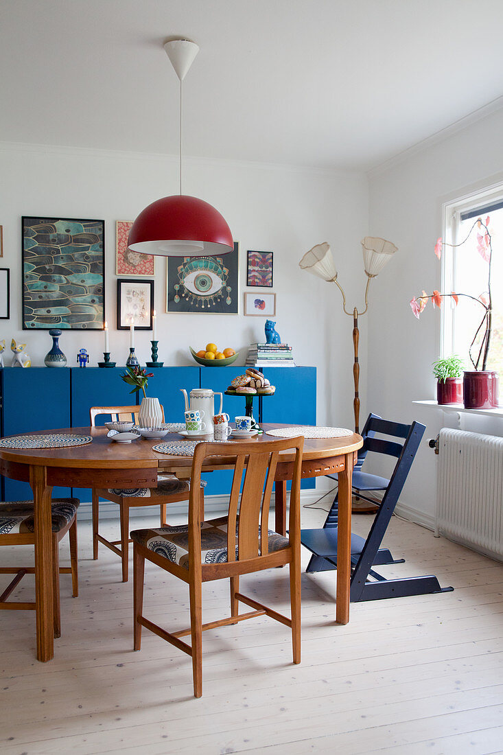 Wooden table and chairs in front of blue sideboard in dining room