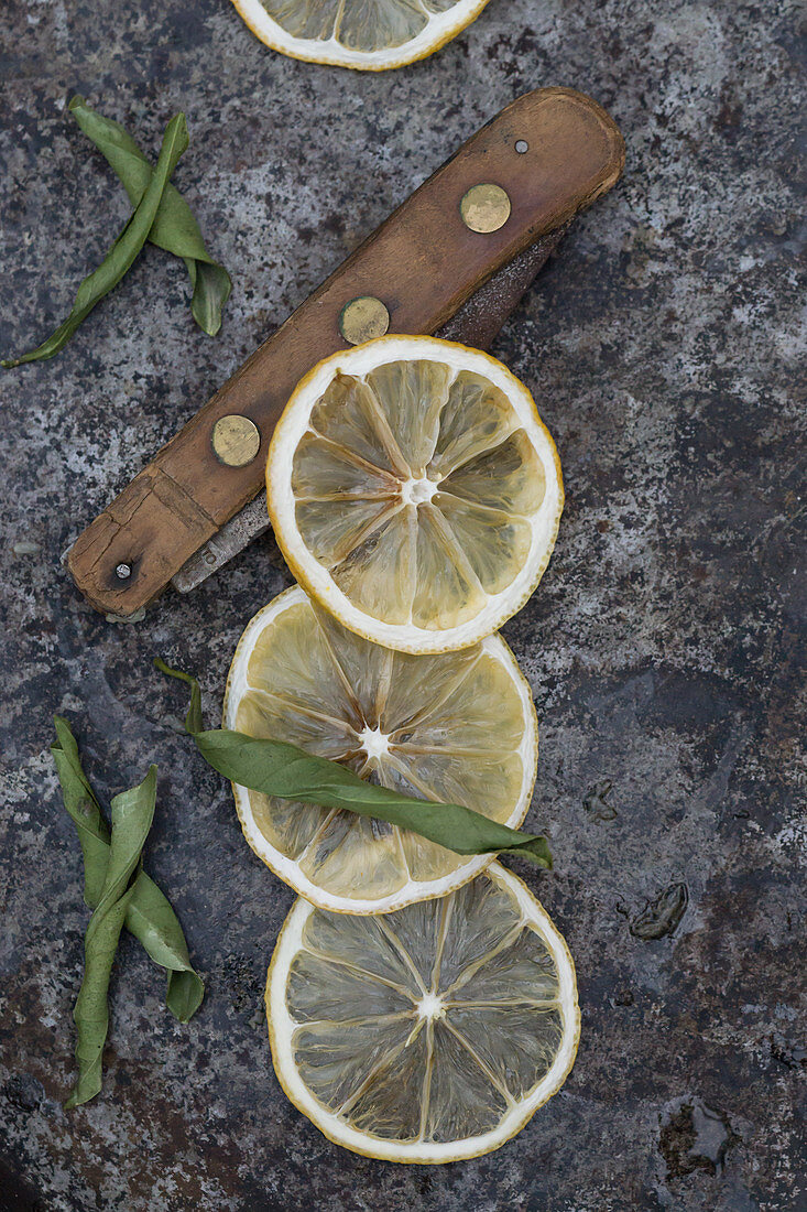 Dried bergamot slices and a vintage folding knife on a gray background