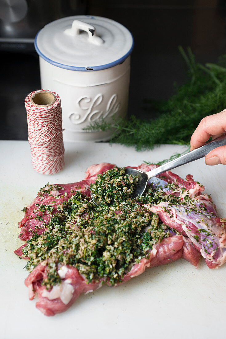 Rohe Lammschulter mit Kräuterpaste bestreichen