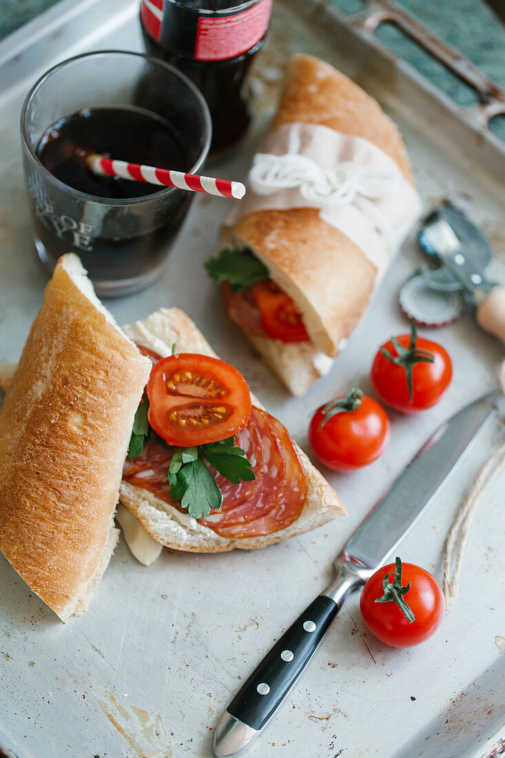 Sandwiches mit Frischkäse, Salami, Tomaten und Petersilie, dazu Cola