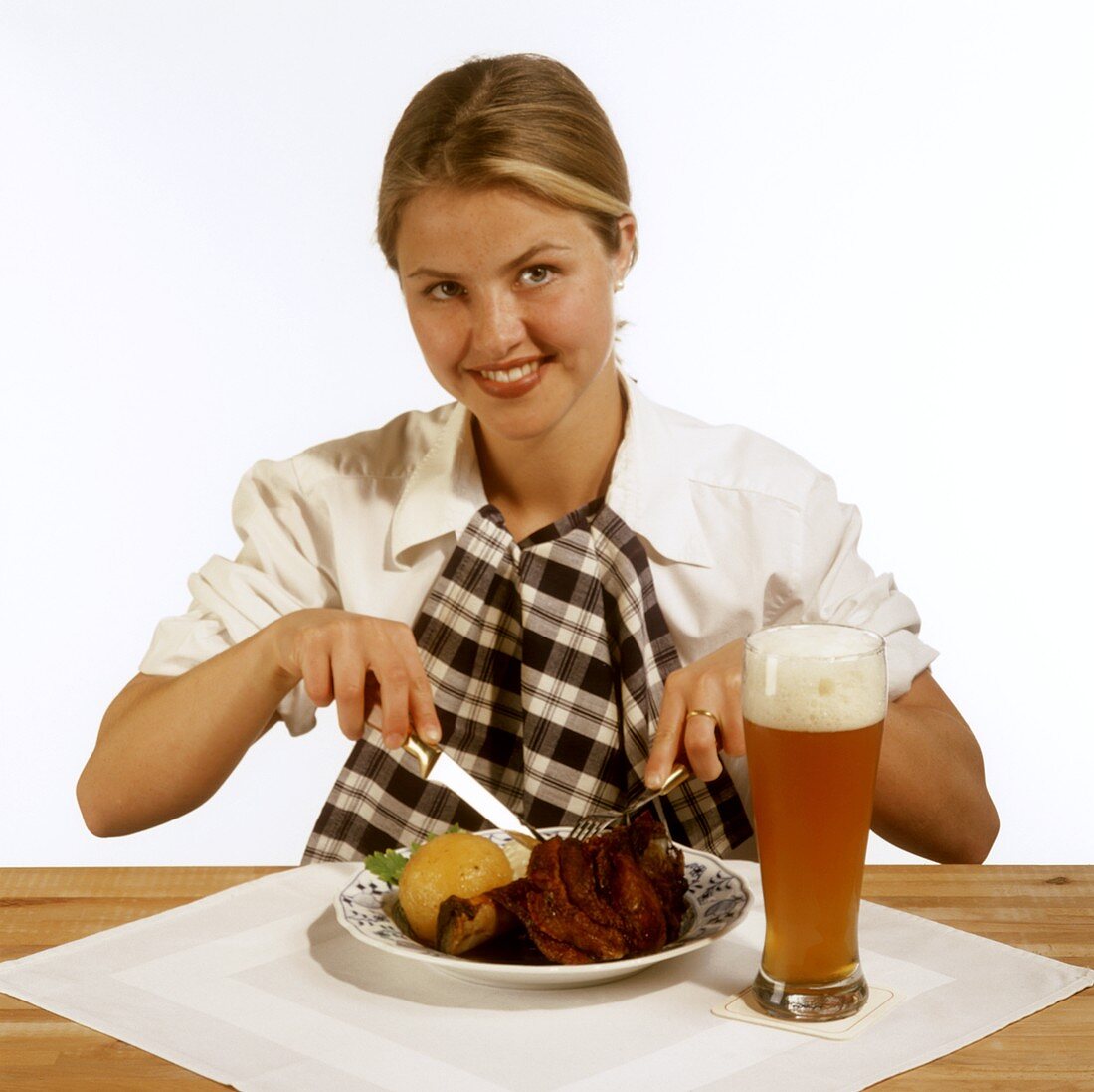 Modell vor Schweinshaxe mit Kloß auf Teller & Glas Weißbier