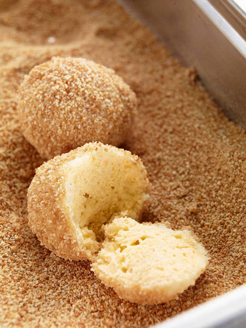 Topfenknödel in gerösteten Zuckerbröseln wenden