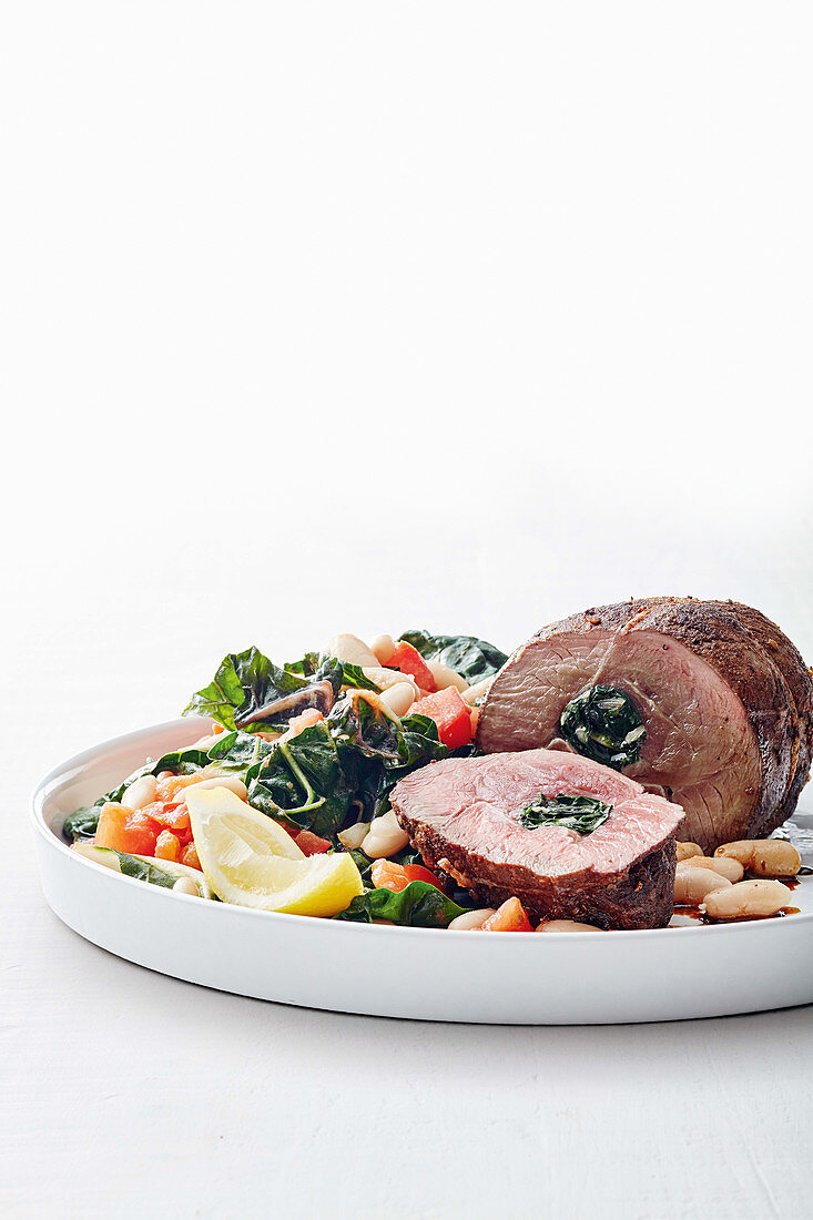 Stuffed roast lamb served with chard and white beans