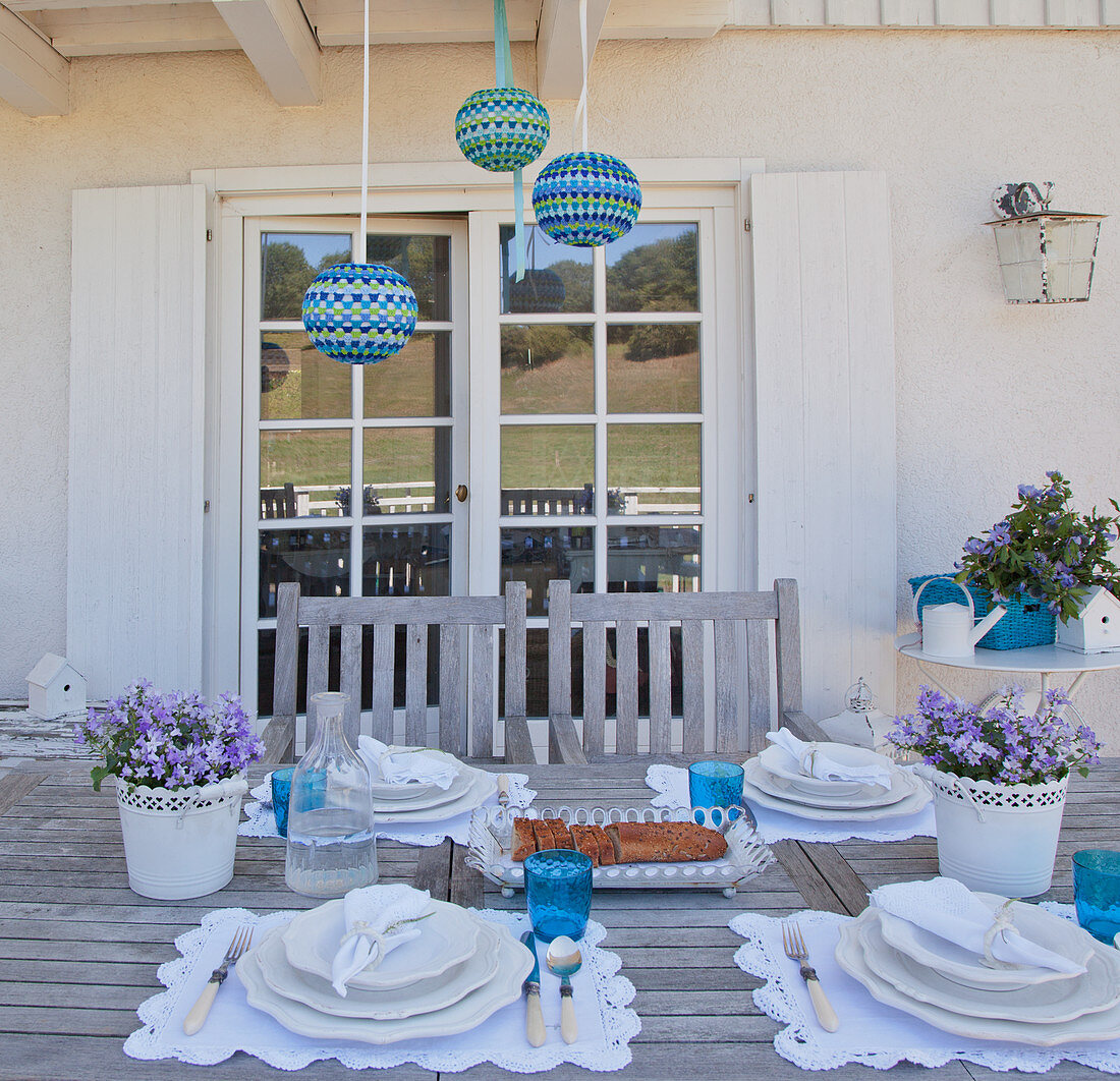 Table with romantic table settings in blue and white on terrace adjoining house