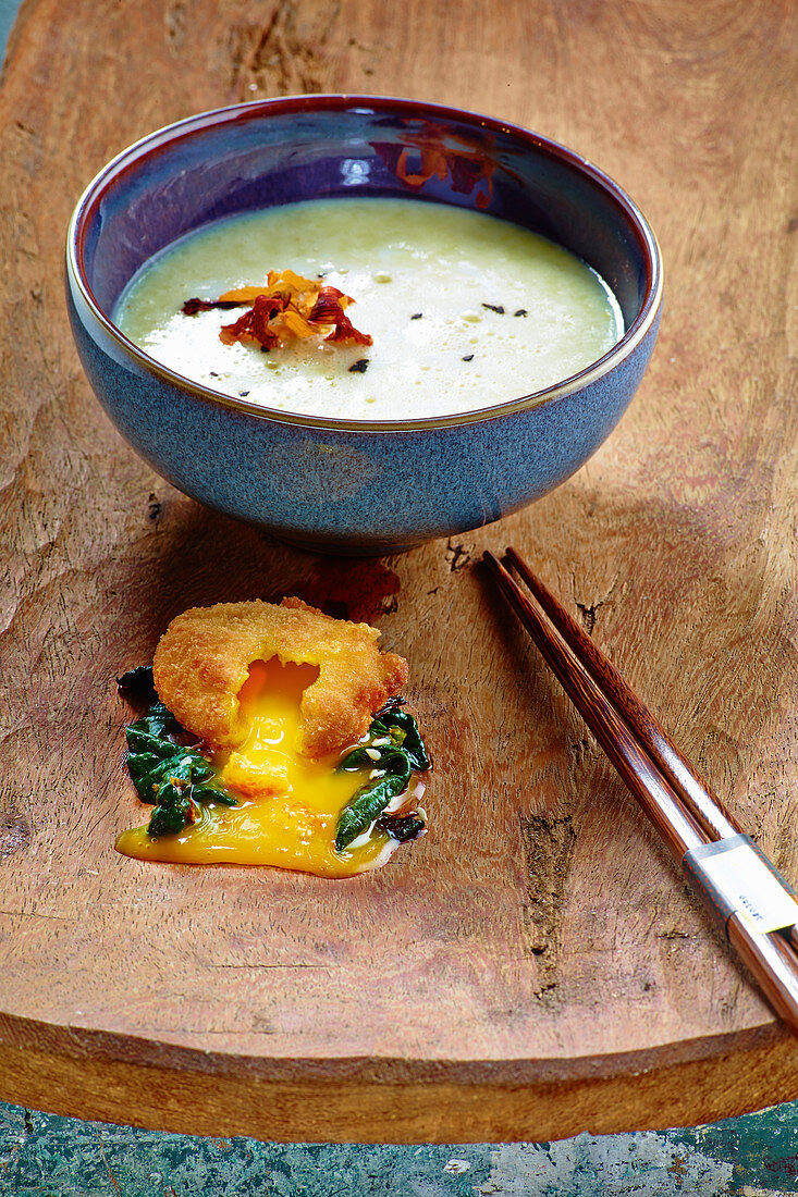 Potato and buttermilk soup with fried egg yolk on oriental spinach