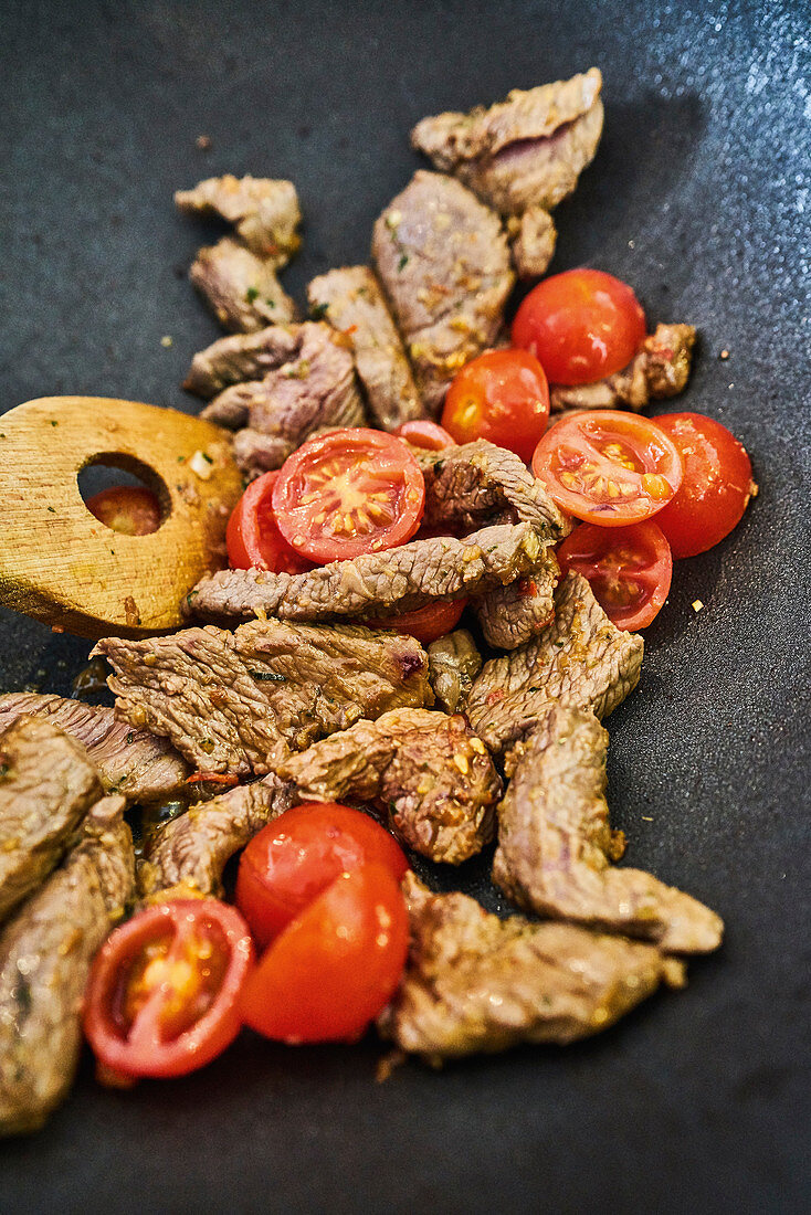 Roast beef with tomatoes in a wok