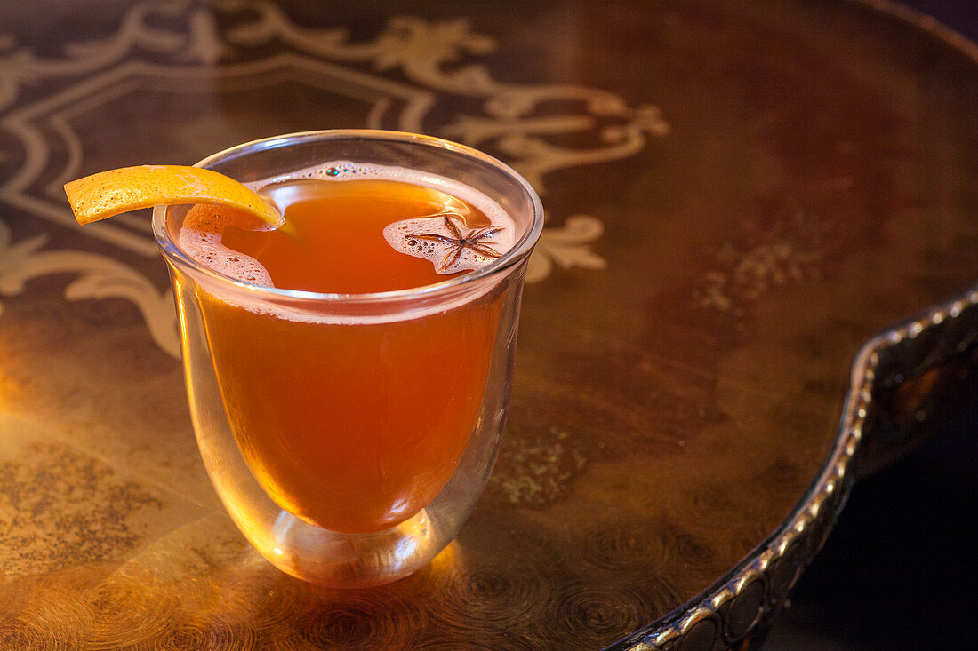Warm whisky cocktail with orange peel and star anise