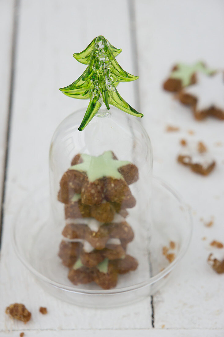 Cinnamon stars with green icing under a glass cloche