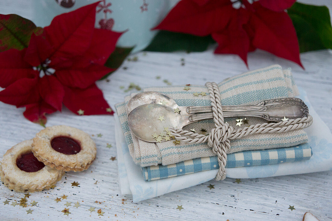 Silver spoons with napkins, jam sandwich biscuits and poinsettias